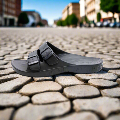 Black sandal on a cobblestone street with blurred background
