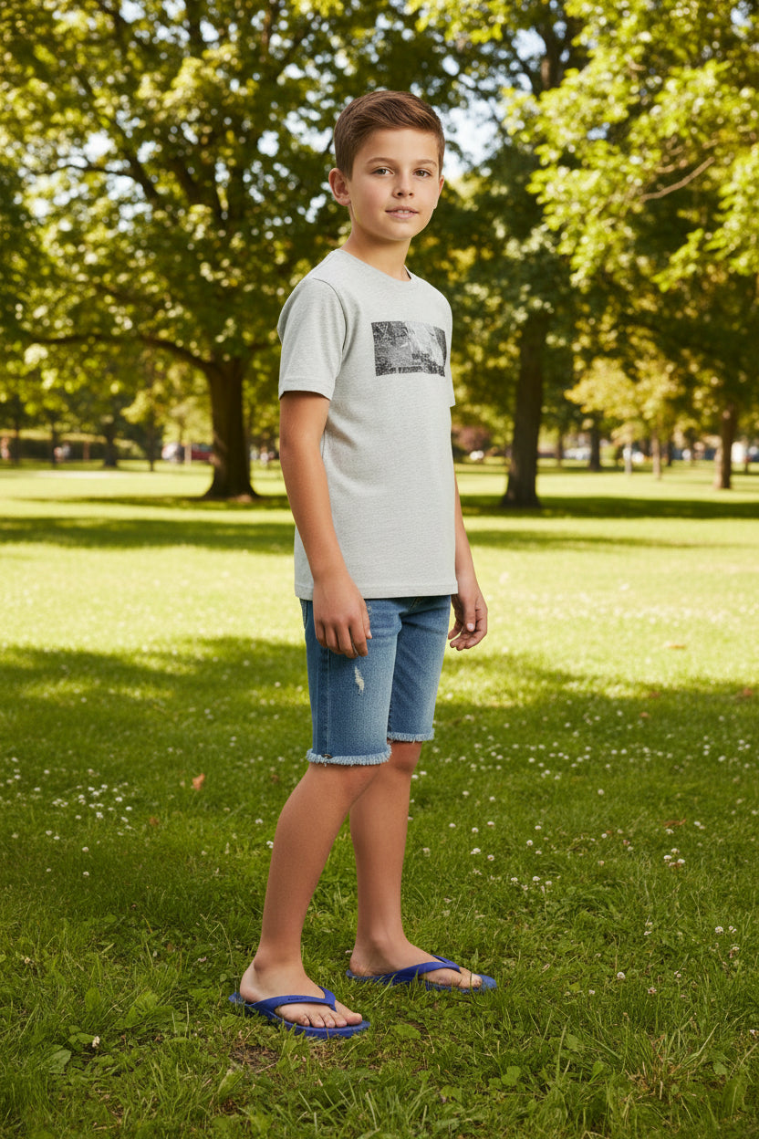 Young boy standing on grass with trees in the background