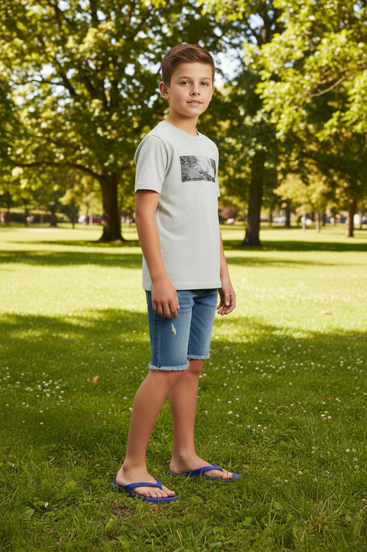 Young boy standing on grass with trees in the background